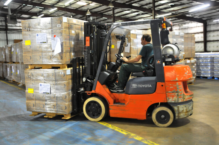 Forklift truck in warehouse. Pallet racking protectors help prevent forklifts damage to racking